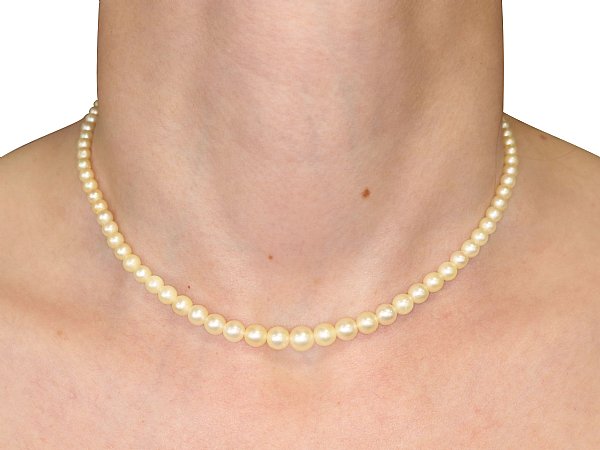 wears vintage pearl necklace